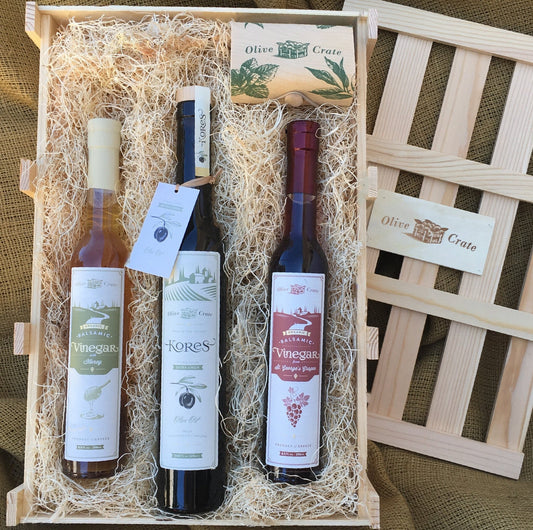 Gift crate with three bottles and an Organic Mountain Oregano box nestled in excelsior, Olive Crate logo lid alongside