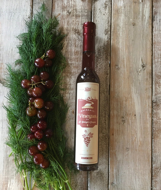 Organic St. George's balsamic vinegar bottle on rustic wood with fresh dill and red grapes