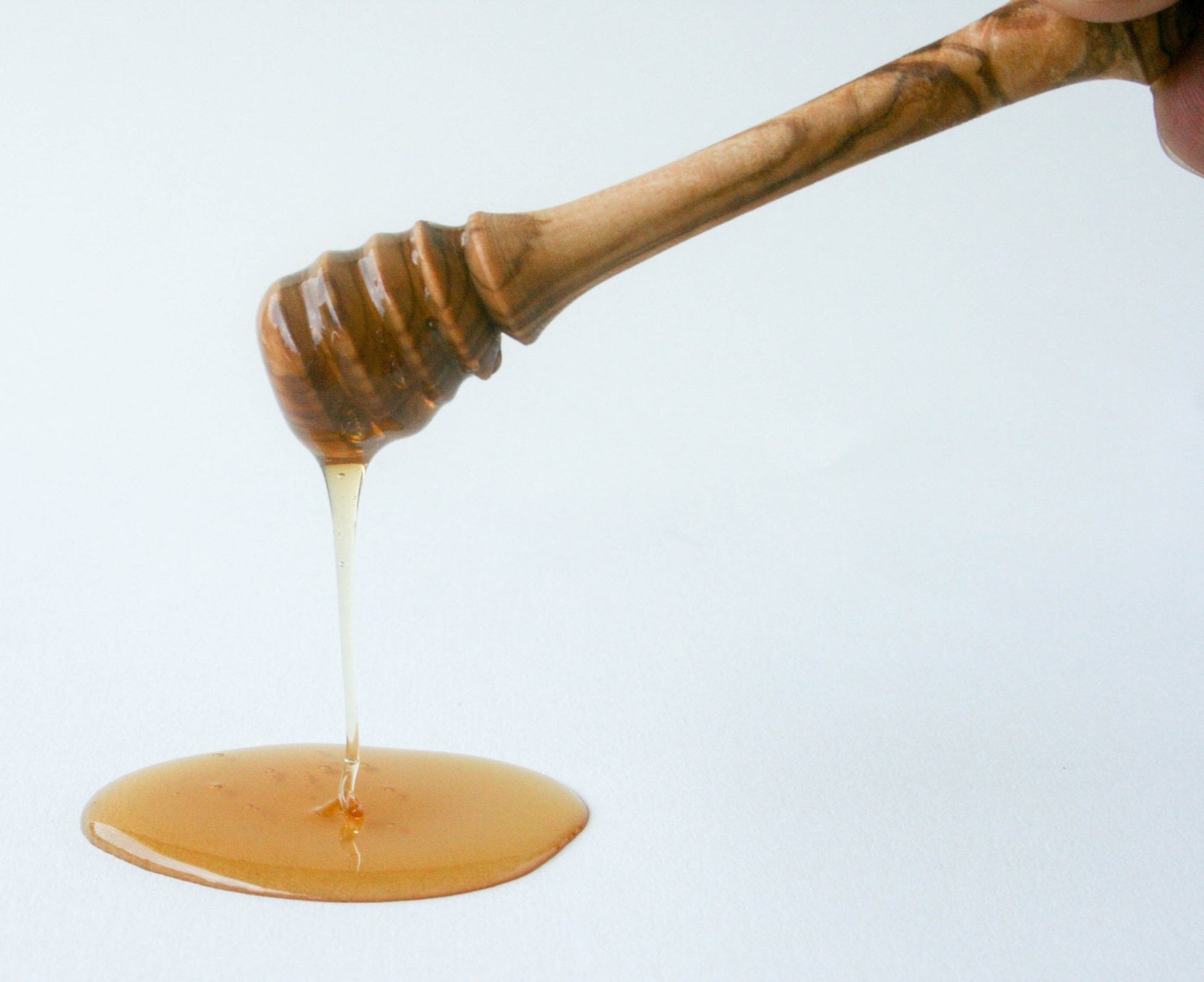 Olive wood honey dipper resting in golden honey – sustainable, handcrafted kitchen tool perfect for drizzling raw honey with style and precision.