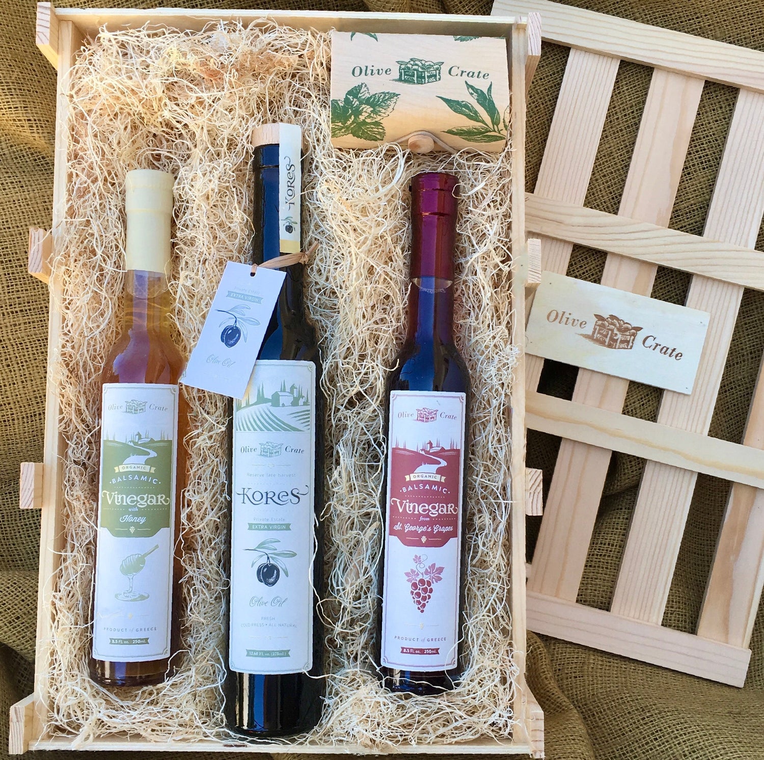 Handcrafted wooden gift crate with lid removed, filled with one extra virgin olive oil and two vinegars from Olive Crate