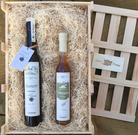 Custom gift crate filled with excelsior holding two artisan bottles, lid with Olive Crate logo resting alongside