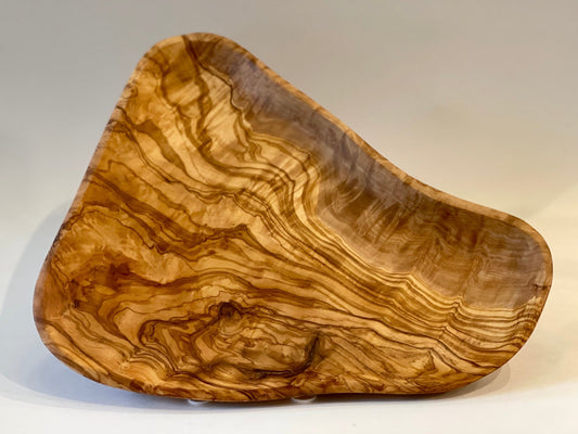 Hand-carved olive wood serving platter with tapered triangular shape and warm swirling grain pattern
