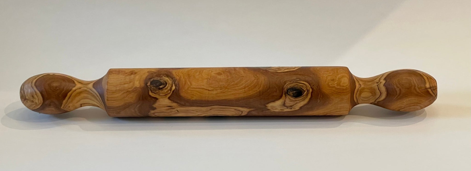 Hand-turned olive wood rolling pin with turned handles, white background