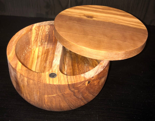 Hand-carved olive wood double salt cellar with two compartments on a black background showing natural grain and marbling